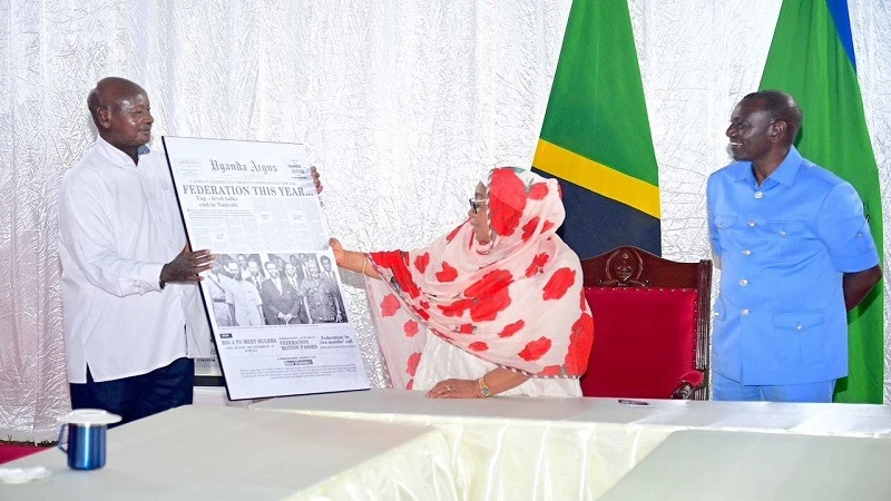 President Samia Suluhu Hassan takes a keen look at a memorial Ugandan newspaper front page poster showing the then leaders of East African countries in a souvenir photo. 
