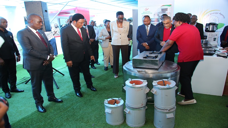 Prime Minister Kassim Majaliwa (2nd L) listens to the Rural Energy Agency's (REA) Director of Renewable Energy Technology Adrera Mwijage (R) on the smart stoves that use less electricity and less charcoal shortly before closing the energy exhibition o