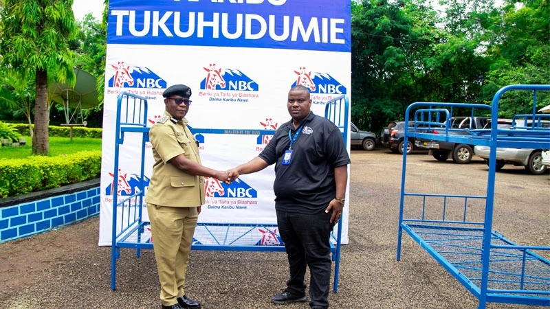 Lazaro Mollel (R), manager of the NBC Bank branch in Moshi municipality, pictured on Wednesday presenting 28 beds to Ramadhani Mungi, commandant of the Moshi-based Tanzania Police School, for use in improving the living conditions of female students.