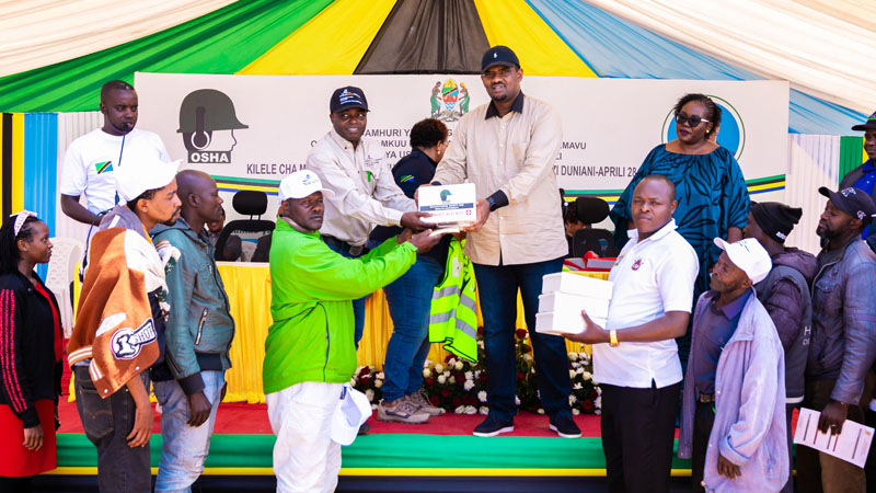 Deogratius Ndejembi (C, in black cap), Minister of State in the Prime Minister’s Office (Labour, Youth, Employment and Persons with Disabilities), and Geita Gold Mining Ltd’s Health, Safety and Environment senior manager Dr Kiva Mvungi (L) .