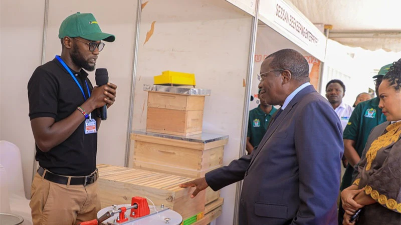Vice President Dr Philip Mpango listens to Christopher Kedendula from Swahili Honey as the VP visited their pavilion during the World Honey Day held in Dodoma yesterday. 
